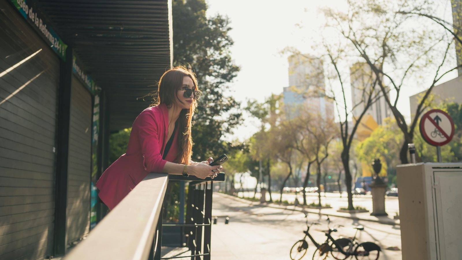 a woman leaning on a rail looking at her cell phone