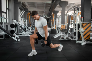 a man doing squats with dumbbells in a gym at The Discovery Park Life Apartments