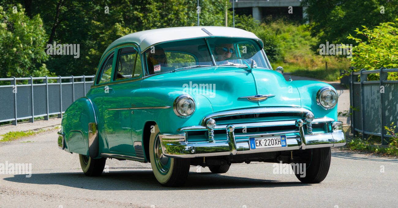 an old blue car is parked on the side of the road